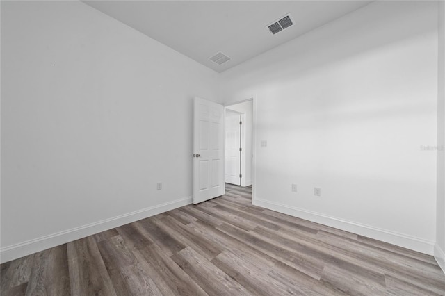 unfurnished room featuring light wood-type flooring, visible vents, and baseboards