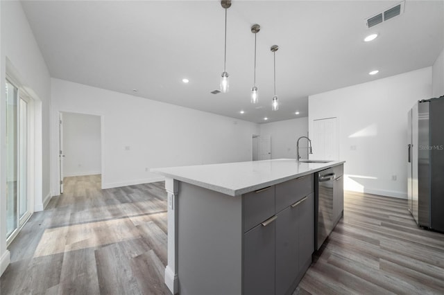 kitchen with a kitchen island with sink, gray cabinetry, visible vents, light countertops, and hanging light fixtures