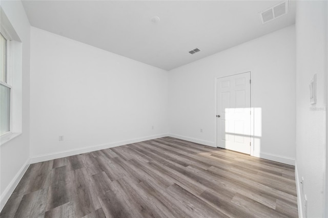 unfurnished room featuring a wealth of natural light, baseboards, visible vents, and wood finished floors