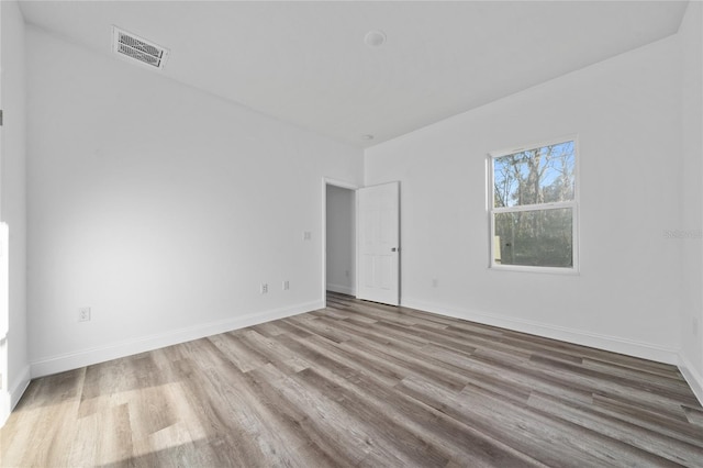 spare room with light wood-style flooring, visible vents, and baseboards