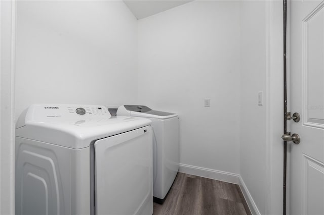 washroom featuring laundry area, washing machine and dryer, baseboards, and wood finished floors