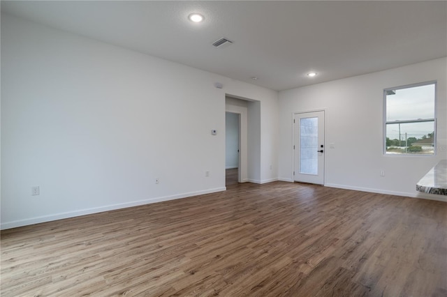 unfurnished room featuring light wood finished floors, recessed lighting, visible vents, and baseboards