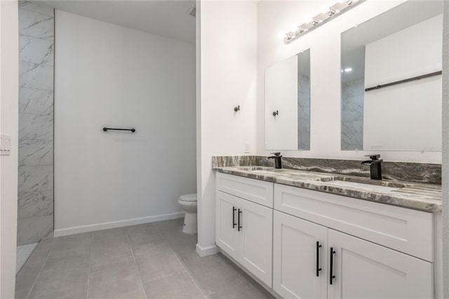 bathroom with toilet, double vanity, baseboards, and a sink