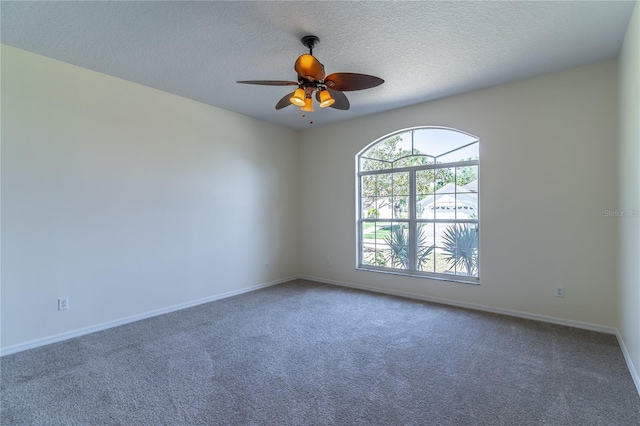 empty room with baseboards, ceiling fan, carpet floors, and a textured ceiling