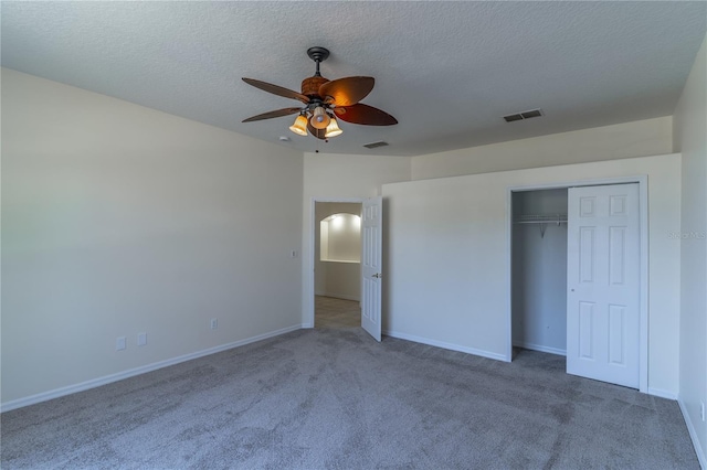 unfurnished bedroom with carpet flooring, a textured ceiling, visible vents, and a ceiling fan