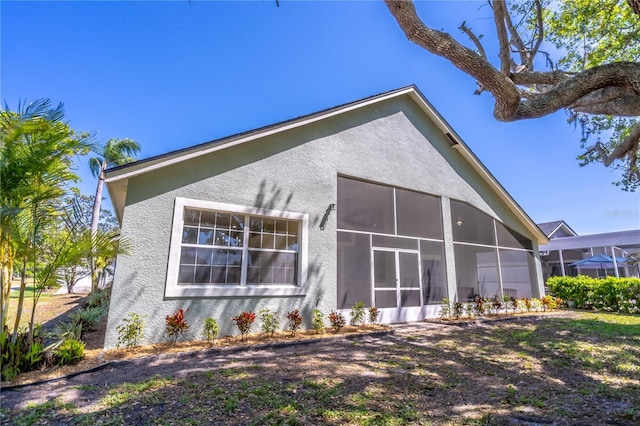 back of property with a sunroom and stucco siding