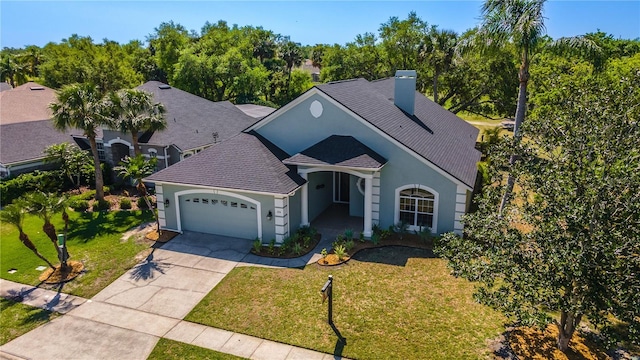 view of front of home with stucco siding, an attached garage, driveway, a front lawn, and a chimney