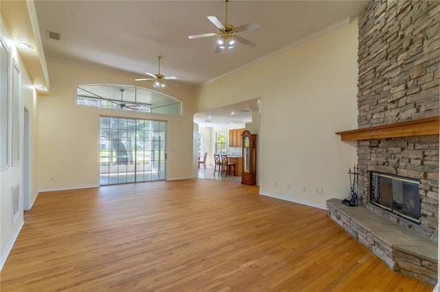 unfurnished living room featuring a ceiling fan, a fireplace, light wood-type flooring, visible vents, and ornamental molding