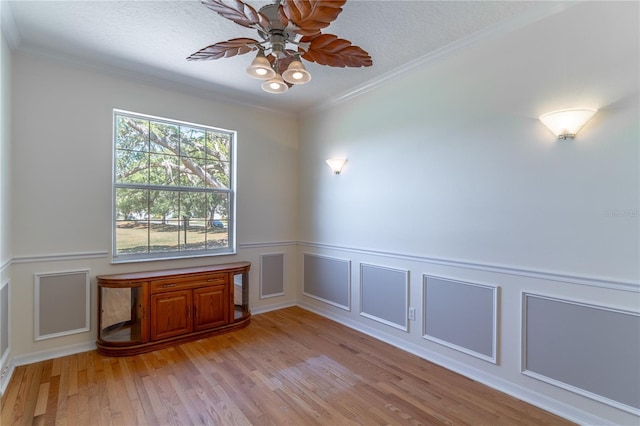 unfurnished room featuring light wood finished floors, ceiling fan, ornamental molding, and a textured ceiling