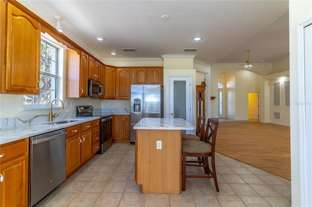 kitchen with a kitchen island, a sink, arched walkways, visible vents, and appliances with stainless steel finishes
