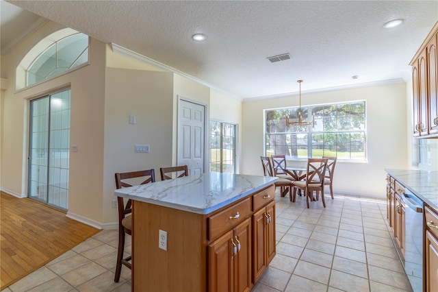 kitchen featuring a breakfast bar area, ornamental molding, stainless steel dishwasher, light tile patterned flooring, and visible vents