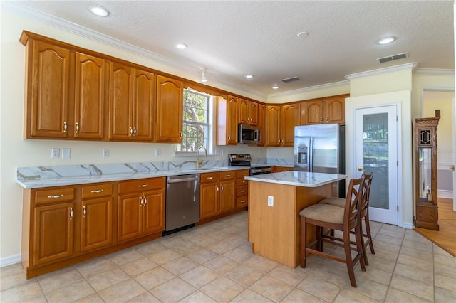 kitchen with a breakfast bar area, visible vents, brown cabinetry, and appliances with stainless steel finishes