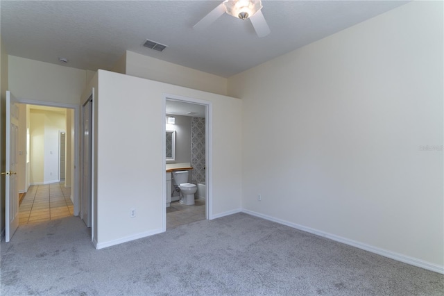 unfurnished bedroom with ensuite bathroom, visible vents, baseboards, ceiling fan, and carpet floors