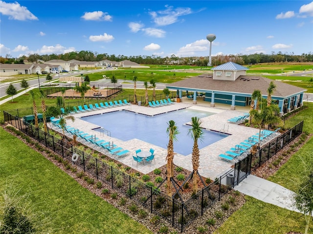 community pool with a patio, a lawn, and fence