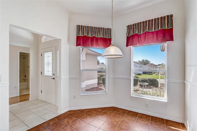 unfurnished dining area with baseboards and tile patterned floors