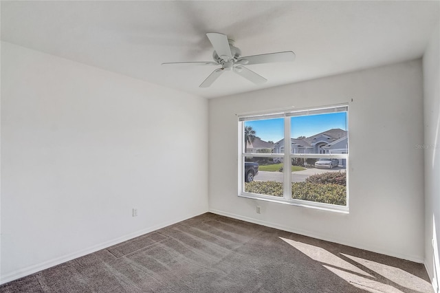 carpeted spare room featuring a ceiling fan and baseboards