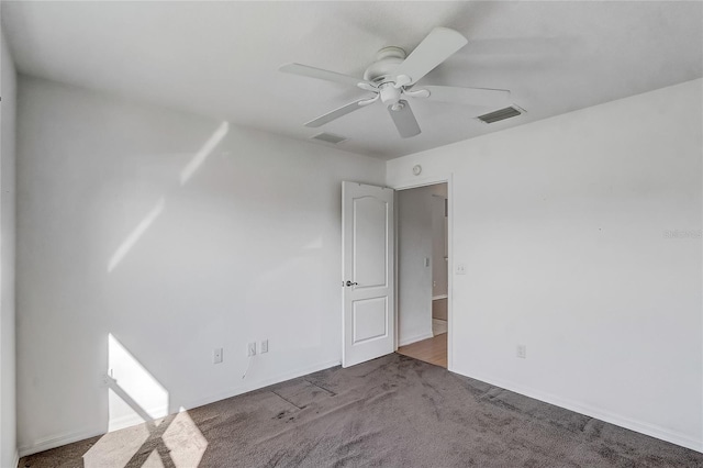 carpeted spare room featuring a ceiling fan and visible vents