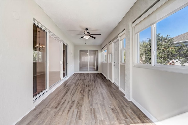 unfurnished sunroom featuring ceiling fan with notable chandelier