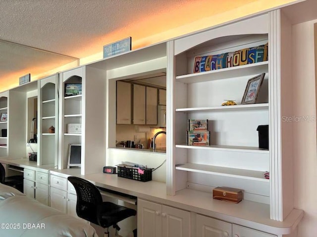 office with built in study area and a textured ceiling