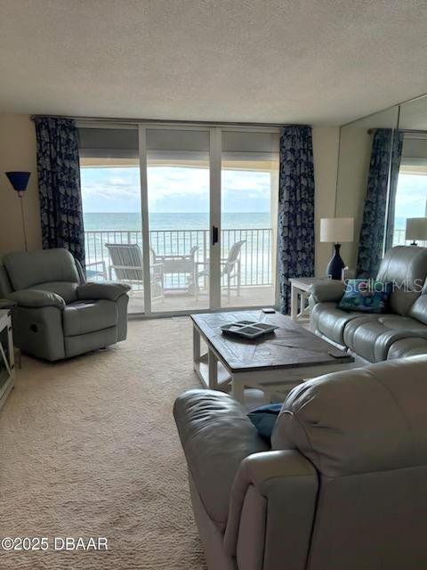 carpeted living room with a water view and a textured ceiling