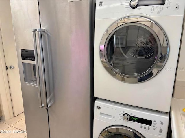 laundry area featuring stacked washing maching and dryer, laundry area, and light tile patterned flooring