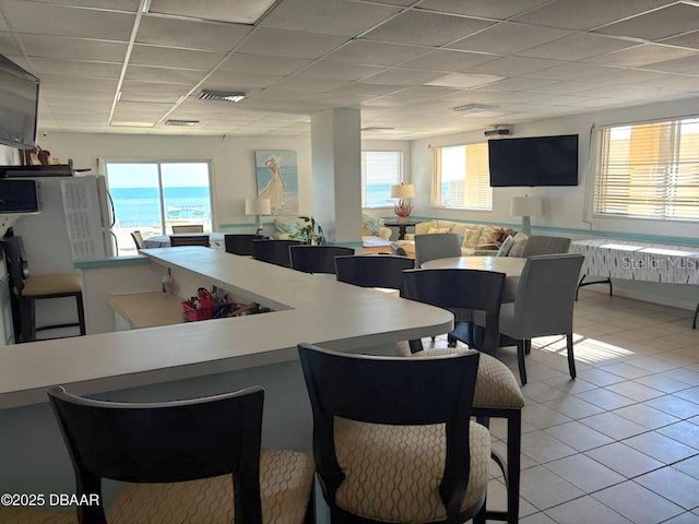 kitchen featuring a water view, light tile patterned floors, and a drop ceiling