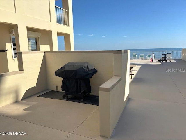 view of patio with grilling area and a water view