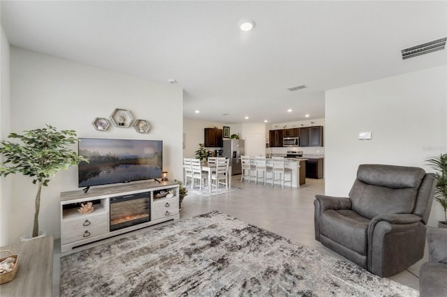 living room with light tile patterned floors, a glass covered fireplace, visible vents, and recessed lighting