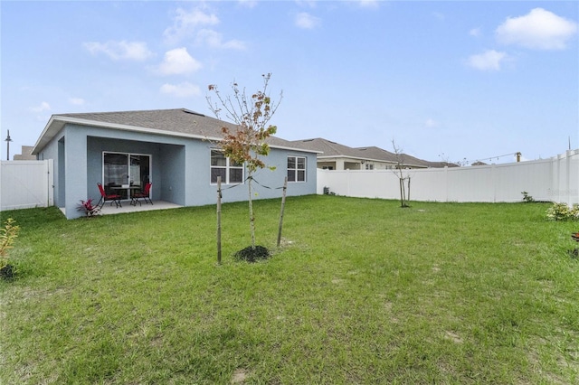 rear view of property featuring stucco siding, a fenced backyard, a lawn, and a patio