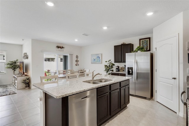 kitchen with a center island with sink, stainless steel appliances, recessed lighting, a sink, and dark brown cabinets