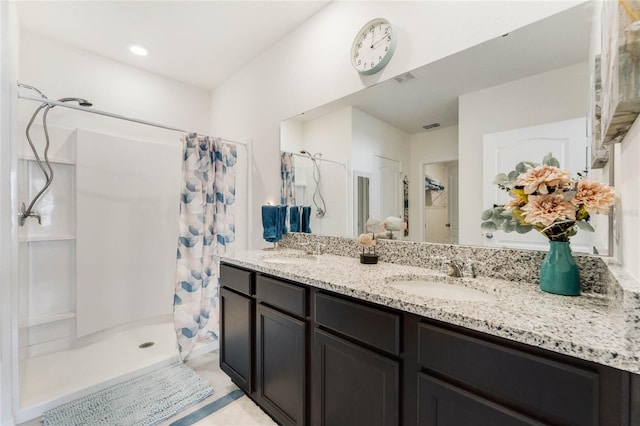 bathroom with double vanity, a stall shower, visible vents, and a sink