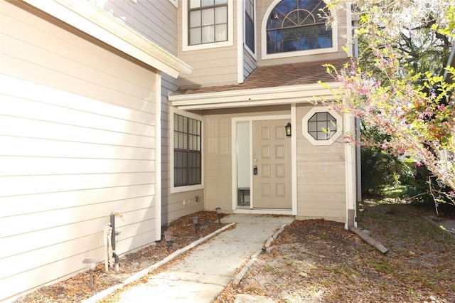 doorway to property featuring roof with shingles