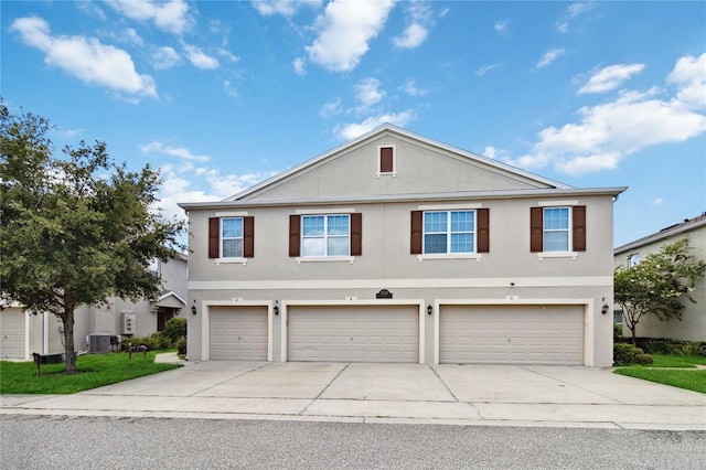 traditional-style house featuring central air condition unit, an attached garage, concrete driveway, and stucco siding