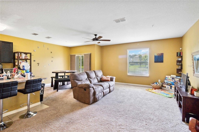 living area with visible vents, light colored carpet, and a textured ceiling