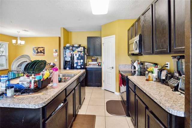 kitchen featuring pendant lighting, light countertops, a kitchen island with sink, light tile patterned flooring, and black appliances