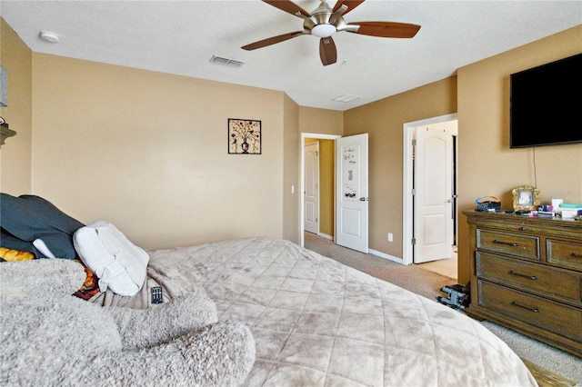 bedroom with light colored carpet, ceiling fan, visible vents, and baseboards