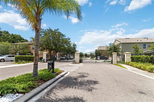 view of road featuring a residential view, a gate, a gated entry, and curbs