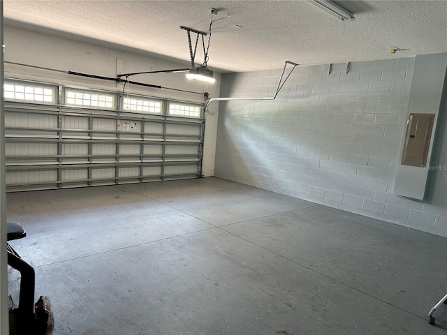 garage featuring concrete block wall, electric panel, and a garage door opener