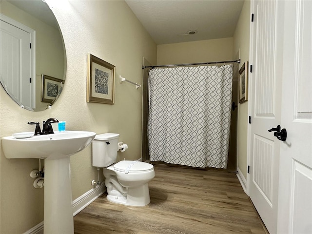 full bathroom with baseboards, a shower with shower curtain, toilet, and wood finished floors