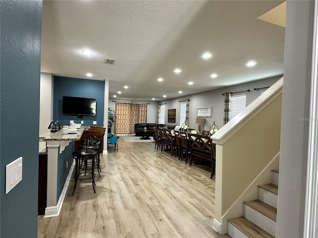 bar featuring visible vents, stairway, a textured ceiling, light wood-style floors, and recessed lighting