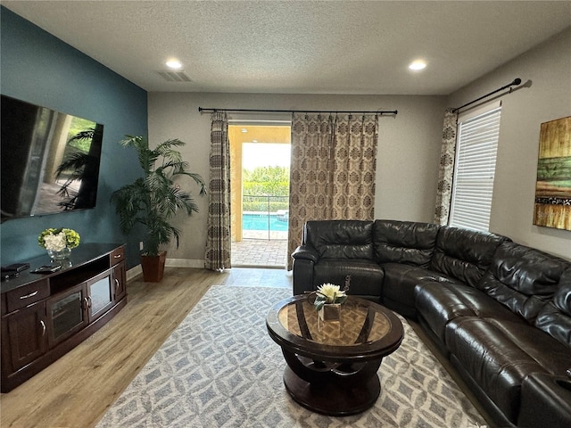 living area with recessed lighting, visible vents, a textured ceiling, light wood-type flooring, and baseboards