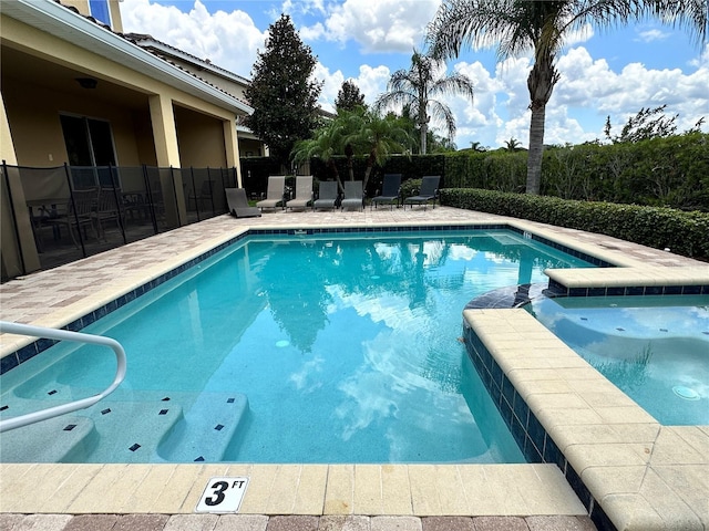 view of swimming pool with a patio area, fence, and a pool with connected hot tub