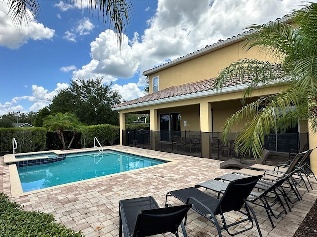 view of pool with a pool with connected hot tub, a patio area, and fence