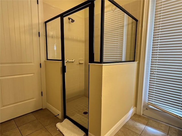 bathroom featuring a stall shower, tile patterned flooring, and baseboards