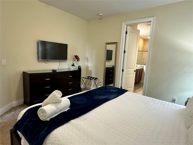 bedroom featuring ensuite bath, baseboards, and light colored carpet