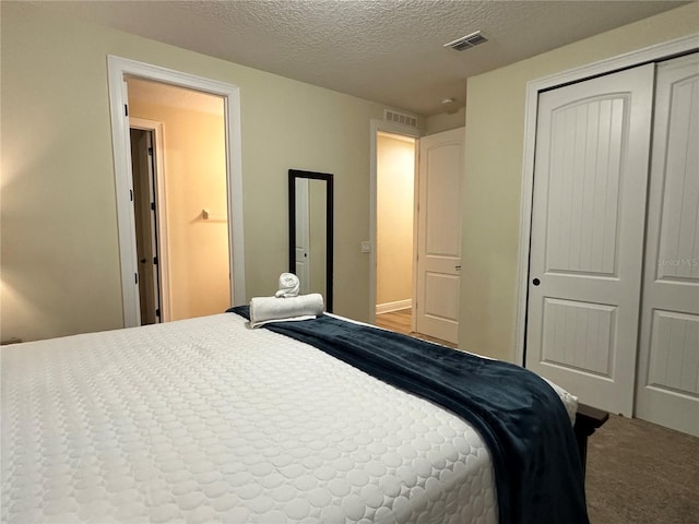 bedroom with carpet, a closet, visible vents, and a textured ceiling