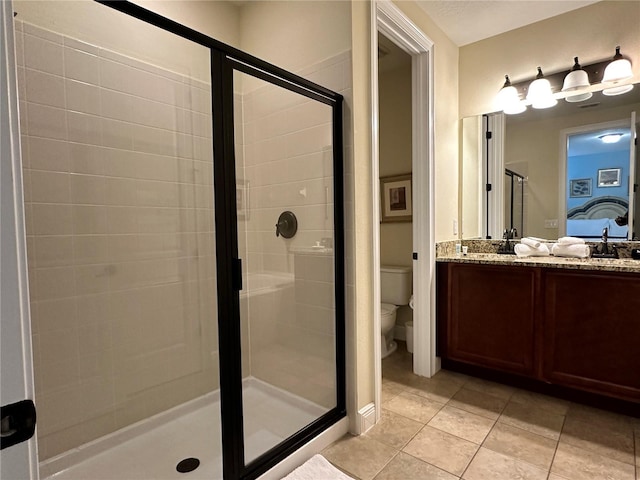 full bath with toilet, a shower stall, vanity, and tile patterned floors