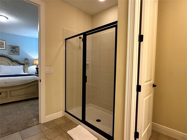 full bath featuring a textured ceiling, baseboards, a shower stall, tile patterned floors, and ensuite bath