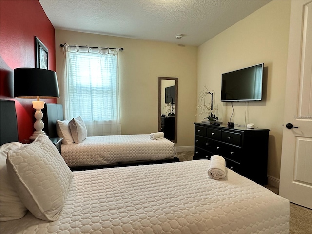 carpeted bedroom featuring a textured ceiling and baseboards