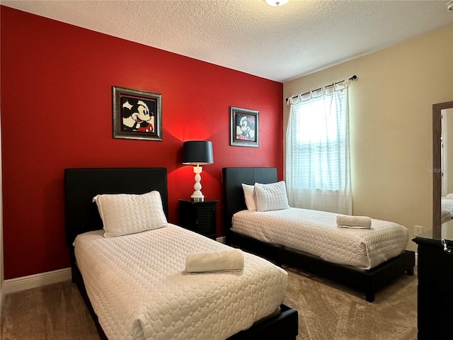 carpeted bedroom featuring an accent wall, a textured ceiling, and baseboards